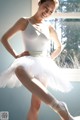 A woman in a white leotard and tutu posing for a picture.