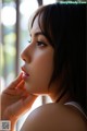 A woman with long black hair is looking out a window.