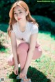 A woman in a white shirt and pink leggings crouching on the ground.