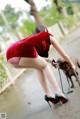 A woman in a red dress is petting a brown dog.