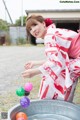 A woman in a red and white kimono playing with colorful balls.