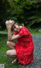 A woman in a red dress crouching on the ground.