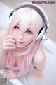 A woman with pink hair wearing headphones and posing for a picture.