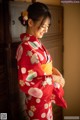 A woman in a red kimono standing in front of a door.