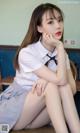 A woman in a school uniform sitting on a chair.