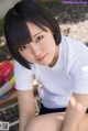 A woman in a white shirt and black shorts sitting on a bench.