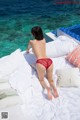 A woman in a red bikini laying on a bed.