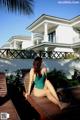 A woman in a green bathing suit sitting on a wooden deck.