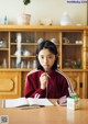 A young girl sitting at a table with a lollipop in her mouth.