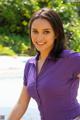 A woman in a purple shirt posing by a pool.