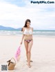 A woman in a bikini walking on the beach.