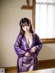 A woman in a purple kimono posing for a picture.