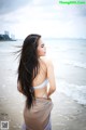 A woman standing on a beach next to the ocean.