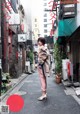 A woman standing in the middle of a narrow street.